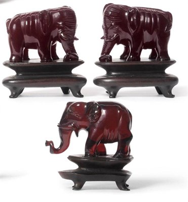 Lot 171 - A Pair of Chinese Red  "Amber " Standing Elephants, circa 1910, the plump animals coiling their...