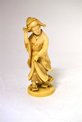 Lot 187 - A Japanese Ivory Okimono, Meiji period, as a maiden holding her hat against the wind, her dress...