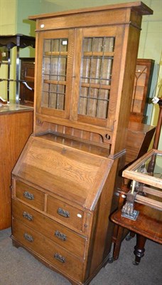 Lot 373 - A small Arts & Crafts bureau bookcase, with double leaded glazed doors above a slope fall...