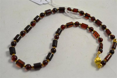 Lot 61 - A strand of amber beads interspersed with gilt beads