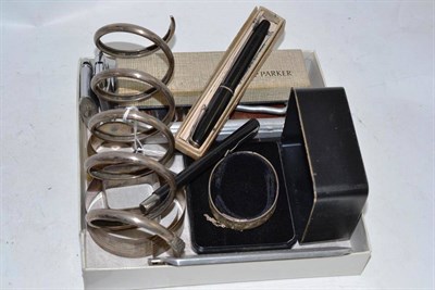 Lot 328 - A silver snake 'bangle', silver napkin rings, fountain pens, razor strap, lighters, etc