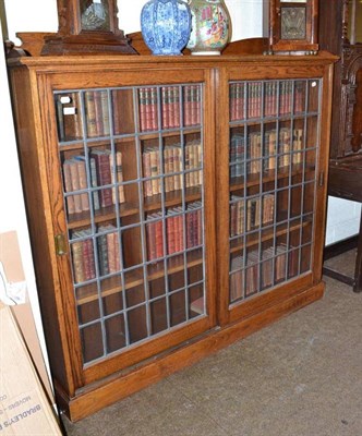 Lot 579 - An oak glass fronted bookcase with sliding doors