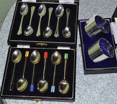 Lot 449 - A pair of cased silver napkin rings, a set of six cased silver and enamel coffee spoons and a cased