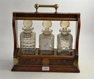 Lot 164 - A late Victorian oak tantalus with three decanters - one replaced
