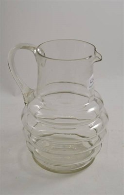 Lot 424 - A glass water jug, early 19th century, the ribbed oval body with cylindrical neck and loop...