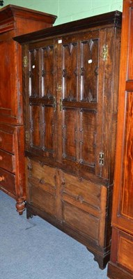 Lot 494 - An oak livery cupboard enclosed by geometric panelled doors