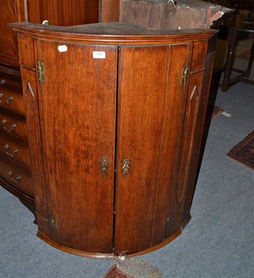 Lot 596 - A Georgian oak bow front corner cupboard