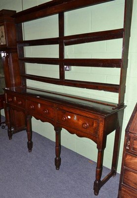 Lot 634 - A Georgian oak three drawer dresser with Delft rack