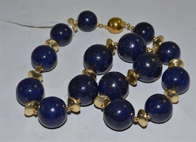 Lot 220 - A dark blue polished bead necklace of lapis lazuli type, with gilt metal spacers and magnetic clasp