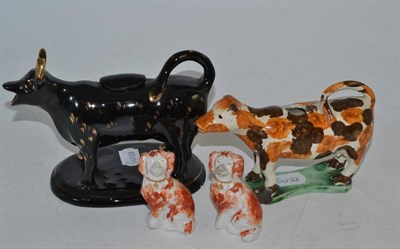 Lot 312 - A Pratt cow creamer, a Jackdale cow creamer and a small pair of seated spaniels (4) (damaged)