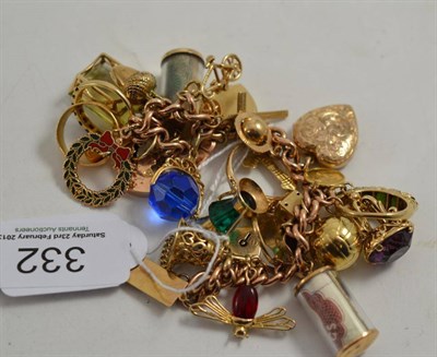 Lot 332 - A charm bracelet hung with twenty-nine charms including dress rings and 22ct gold band ring