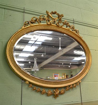 Lot 458 - An Edwardian oval bevelled wall mirror, in a gilt wood and gesso lattice moulded frame, with ribbon