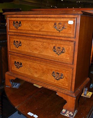 Lot 556 - A small reproduction walnut three drawer chest