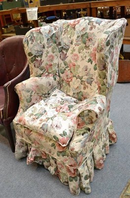 Lot 719 - A Georgian style wing armchair with loose floral cover