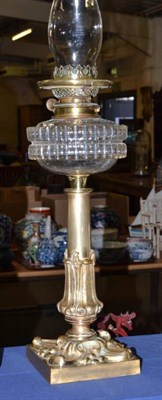 Lot 144 - A William IV style brass oil lamp with stiff leaf sheathed stem and clear glass font
