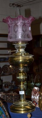 Lot 147 - A brass oil lamp with etched cranberry glass shade