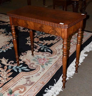Lot 417 - A mahogany fold-over card table with shaped edge and turned legs