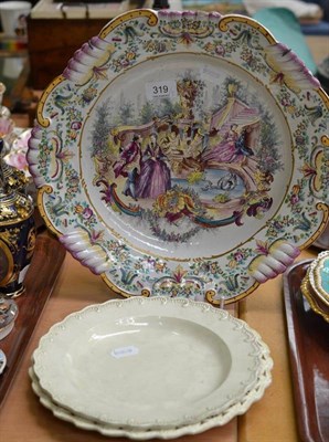 Lot 319 - A French faience large dish painted with lovers in landscapes and two creamware plates (3)