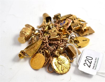 Lot 220 - A 9ct gold charm bracelet hung with approximately thirty gold and yellow metal charms,...