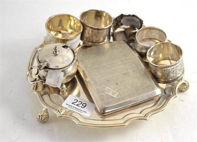 Lot 229 - A modern engraved silver waiter, a cigarette case, five silver napkin rings and a mustard pot