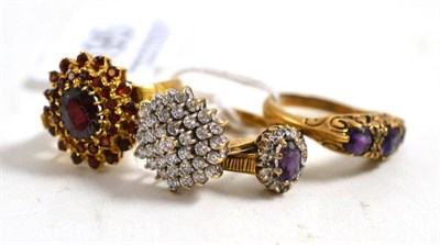 Lot 195 - Four 9ct gold stone set dress rings - a garnet cluster, a cubic zirconia cluster and two...