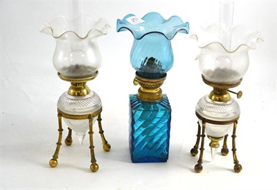 Lot 257 - Three glass and gilt metal oil lamps with shades and chimneys