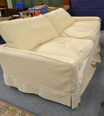 Lot 504 - A large cream upholstered four seater sofa with feather filled pillows