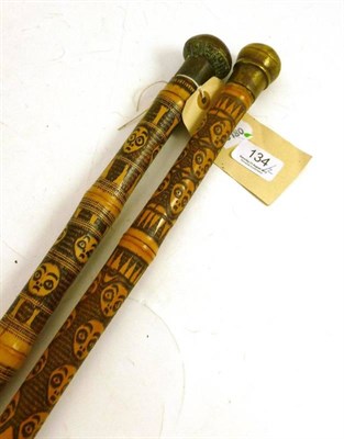 Lot 134 - Two West African bamboo walking sticks, each incised and black stained with bands of human...