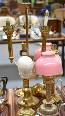 Lot 175 - A brass two branch candelabrum, a pair of foliate decorated brass candle lamps with opaque pink...