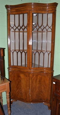 Lot 520 - A reproduction walnut serpentine fronted floor standing display cabinet with astragal glazed...