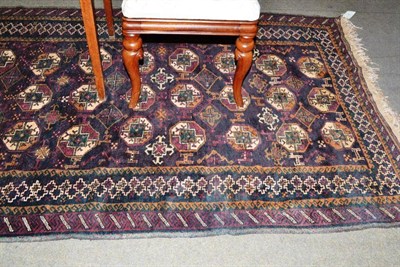 Lot 546 - Balouch Rug West Afghanistan, the aubergine field with three columns of octagonal guls enclosed...