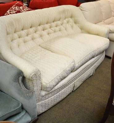 Lot 557 - A cream upholstered button back three seater settee