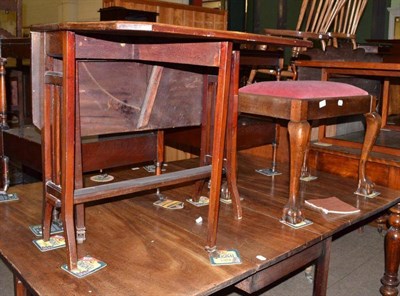 Lot 603 - An Edwardian mahogany Sutherland table with twin drop leaves and a carved mahogany stool in...