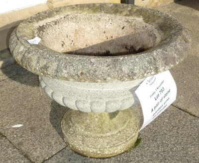 Lot 793 - A pair of stone garden urns on plinths