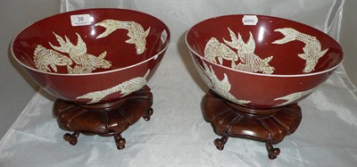 Lot 38 - A pair of large Chinese porcelain bowls, with white goldfish on coral ground, on carved wooden...