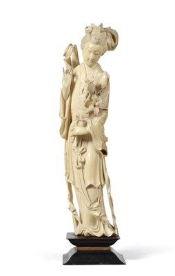 Lot 210 - A Chinese Ivory Figure of a Maiden, late Qing Dynasty, standing, her hair up, wearing flowing...