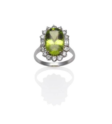 Lot 317 - An 18 Carat White Gold Peridot and Diamond Cluster Ring, the oval mixed cut peridot within a border