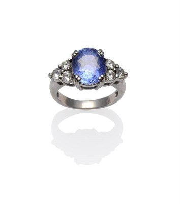 Lot 318 - A Sapphire and Diamond Ring, the cornflower blue oval mixed cut sapphire between a trio of...