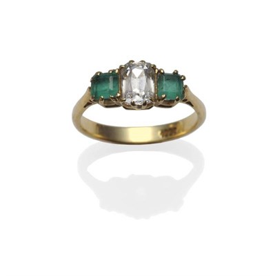 Lot 349 - A Diamond and Emerald Three Stone Ring, the old cut diamond flanked by a step cut emerald on...