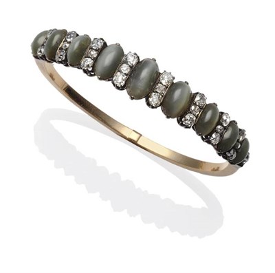 Lot 352 - A Chrysoberyl and Diamond Bangle, nine graduated oval cabochon cat's-eye chrysoberyls spaced by...