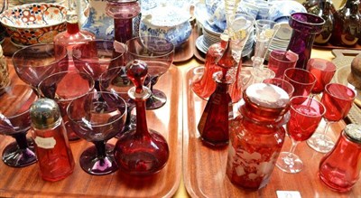 Lot 23 - A quantity of cranberry glass including bells, six wines, two casters, bulb vases and amethyst...