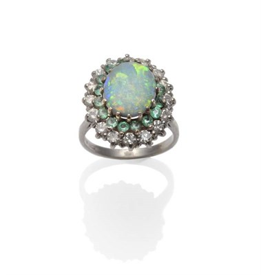 Lot 377 - An 18 Carat White Gold Opal, Emerald and Diamond Cluster Ring, the oval opal within a border of...