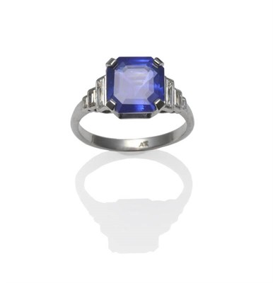 Lot 383 - A Sapphire and Diamond Ring, the octagonal step cut sapphire in a white four claw setting, to three