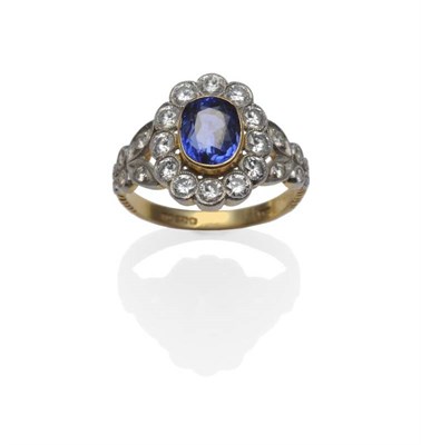 Lot 418 - An 18 Carat Gold Sapphire and Diamond Cluster Ring, an oval mixed cut sapphire in a yellow...