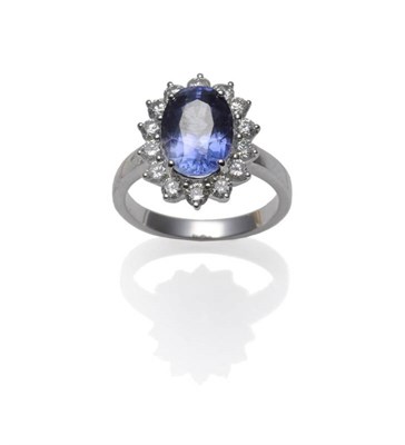 Lot 422 - A Sapphire and Diamond Cluster Ring, the oval cut sapphire within a border of fourteen round...