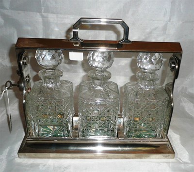 Lot 28 - A three bottle tantalus in a plated stand