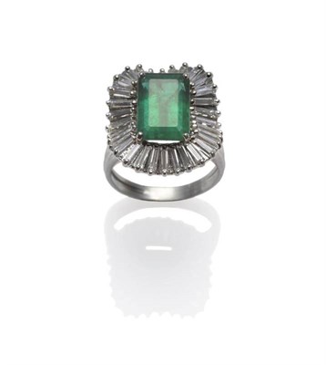 Lot 423 - An Emerald and Diamond Ring, the emerald-cut emerald within an undulating border of baguette...