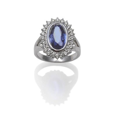 Lot 424 - A Sapphire and Diamond Cluster Ring, an oval mixed cut sapphire within a border of round...