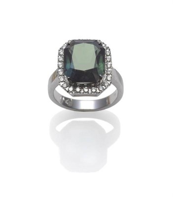 Lot 426 - A Green Sapphire and Diamond Cluster Ring, the octagonal step cut sapphire in a white corner...