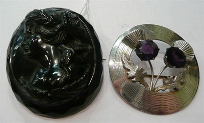 Lot 101 - A jet brooch carved with the profile of a maiden and a Scottish style brooch with thistle...